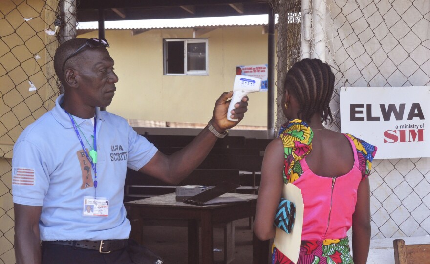 A unidentified family member (right) of a 10-year-old boy that contracted Ebola has her temperature measured by a health worker outside an Ebola clinic on the outskirts of Monrovia, Liberia, on Nov. 20. Liberia, Guinea and Sierra Leone have now gone 42 days without a single reported case of Ebola.