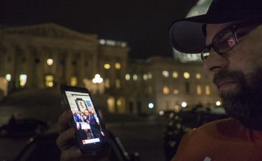 Outside the U.S. Capitol on Thursday, a supporter watches the proceedings being live-streamed from the House floor by Democrats taking part in a sit-in.