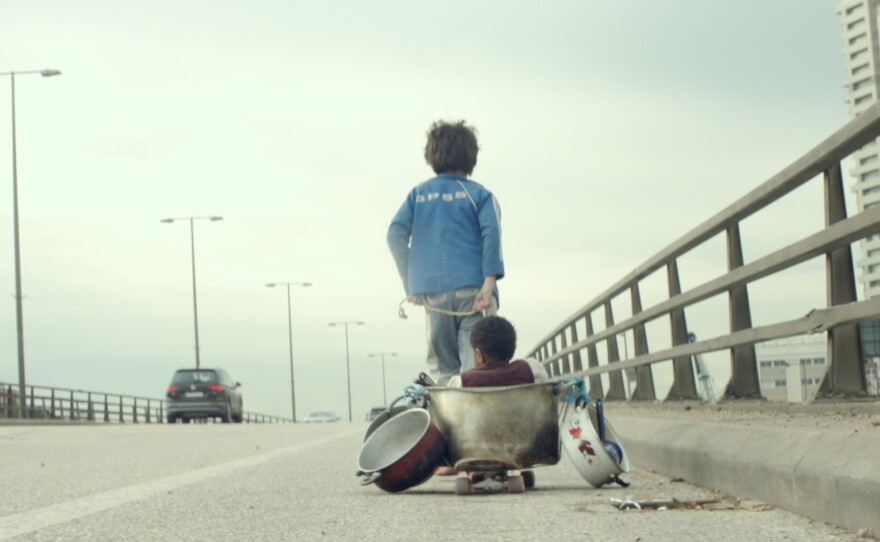 Zain (Zain Al Rafeea) pulls companion Yonas (Boluwatife Treasure Bankole) on a makeshift wagon in the movie <em>Capernaum.</em>