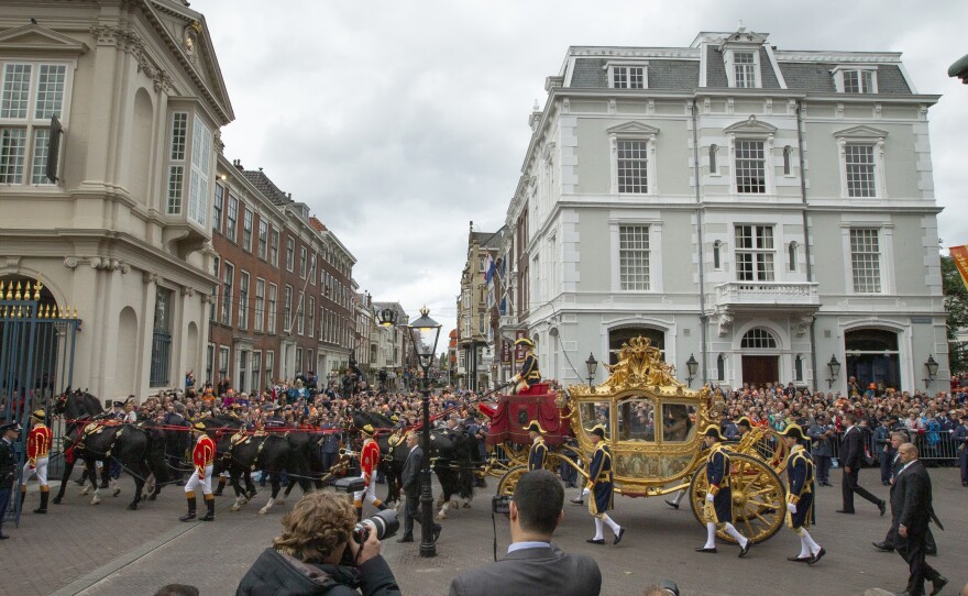 Footmen walk alongside the Golden Carriage as Netherlands' King Willem-Alexander and Queen Maxima arrive at Noordeinde Palacey on Sept. 17, 2013.