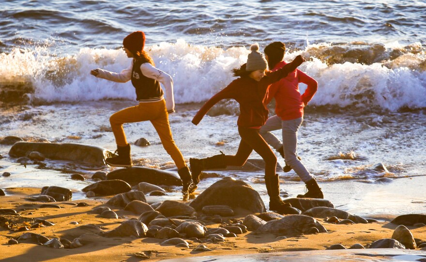 Schoolkids play in the fading light and surf along a small Nuuk beachfront.