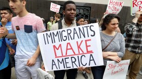 Torianto Johnson, a freshman at Pioneer High School in Ann Arbor, holds a sign supporting immigrants during a rally outside a federal courthouse in Detroit, May 16, 2017.
