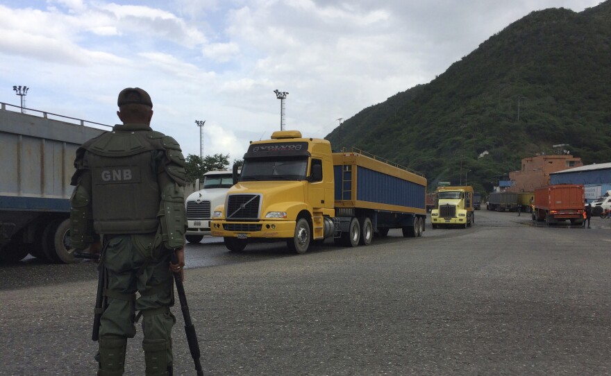A Venezuelan soldier watches over cargo trucks leaving the port in Puerto Cabello, which handles the majority of the country's food imports. Across the chain of command, from high-level generals to the lowest foot soldiers, military officials are using their growing power over the food supply to siphon off wealth for themselves.