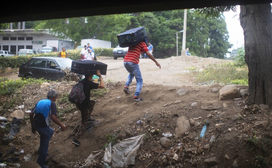 Young men carry luggage from Venezuela into Colombia under the Simón Bolívar International Bridge. Millions of Venezuelans have left the country in recent years.