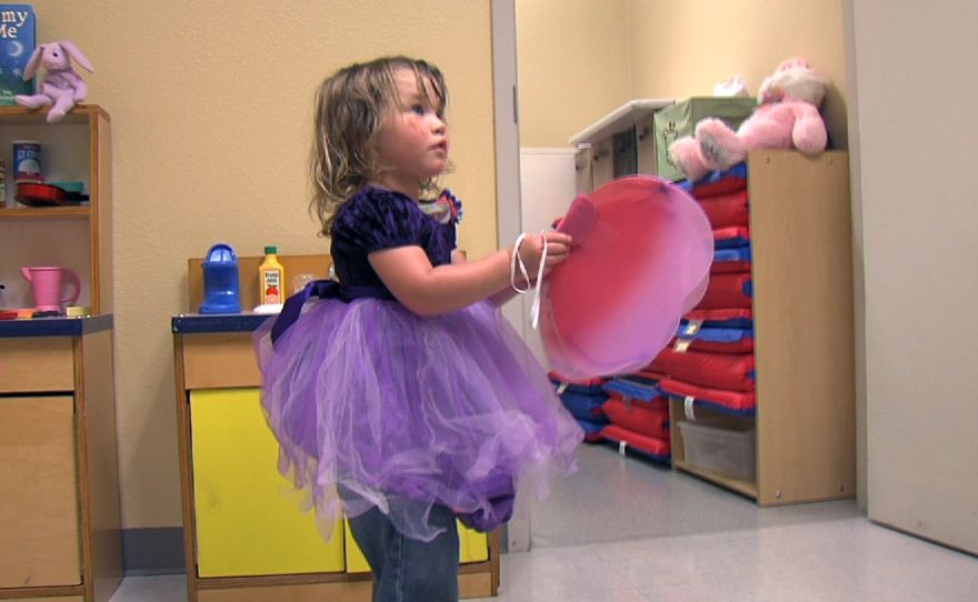Two-year-old Rebeka plays dress-up in a purple princess dress and pink butterfly wings at the Rescue Mission's Children's Center, Sept. 9, 2014.