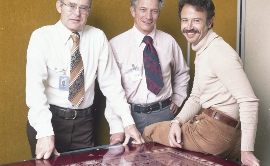 Intel executives Robert Noyce, Gordon Moore, and Andy Grove standing over a mask design on 10th anniversary of Intel.