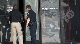 Police officers enter the Armed Forces Career Center through a bullet-riddled door after a gunman opened fire on the building in Chattanooga, Tenn., , July 16, 2015. 