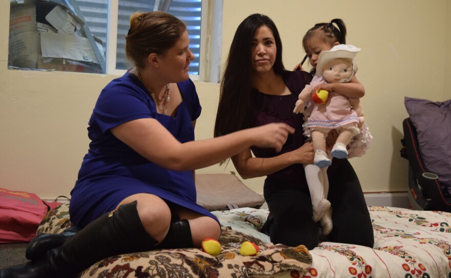 Sandra Lopez holds her daughter, Areli, next to Rev. Shawna Foster in the basement of the Two Rivers Unitarian Universalist parsonage in Carbondale, Colo.