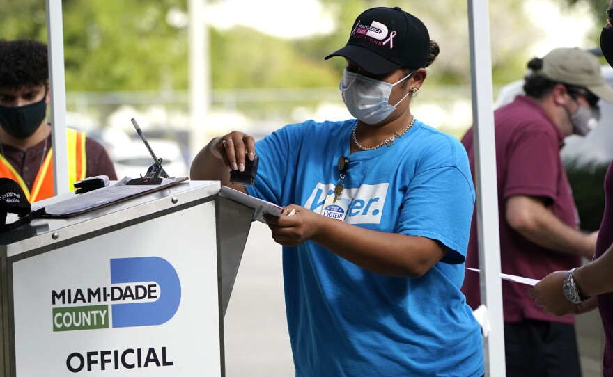 An election worker stamps a vote-by-mail ballot dropped off by a voter before placing it in an official ballot drop box at the Miami-Dade County Board of Elections in Doral, Fla., in October 2020. The Florida state Senate on Monday passed a bill that would reduce access to drop boxes.