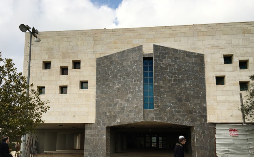 A settler walks past a new building in Beit El's yeshiva complex. Trump's pick for ambassador, David Friedman, has raised money for the yeshivas in Beit El.