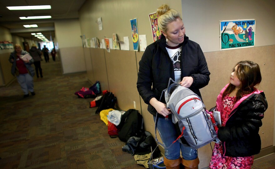 Ashley Bones talks to her stepdaughter, Faith, as she picks her up from elementary school in Watford City, N.D.