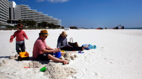 A family from New Orleans visits a beach in Pensacola, Fla., just before spring break season last month. In the distance, workers continue to clean up after the Deepwater Horizon oil spill.