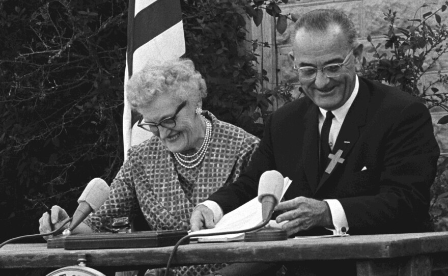 President Lyndon B. Johnson signs the ESEA in 1965 with Kate Deadrich Loney, the President's first schoolteacher.