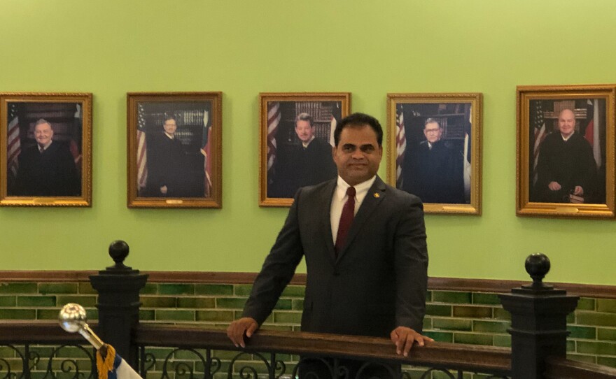 K.P. George, pictured in the historic Fort Bend County Courthouse in Richmond, Texas, stands before the photos of all the previous County Judges who preceded him in the office. The Indian immigrant is the first minority ever elected to the seat.