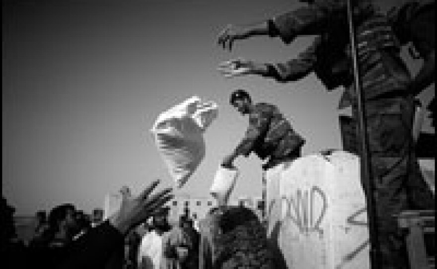 Afghan commandos throw bags of rice from the back of their truck during a humanitarian aid drop in the village of Kuhak, in Zerkoh Valley, western Afghanistan.