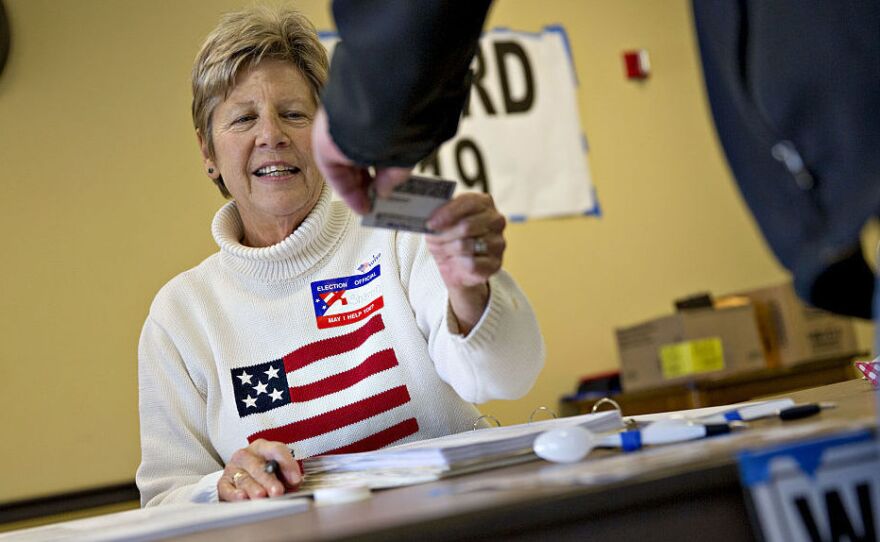 A poll worker checks the identification of a resident at a polling location during the Wisconsin presidential primary on April 5.