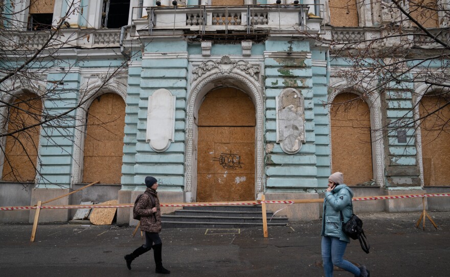 People walk in front of a historic building in Kharkiv that was damaged by a Russian strike.