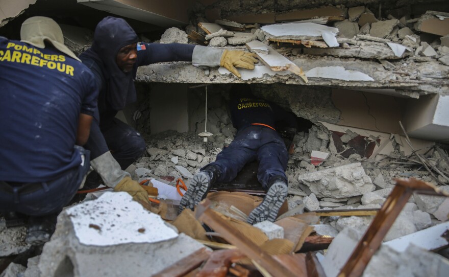<strong>Sun. Aug. 15:</strong> Firefighters search for survivors inside a collapsed building in Les Cayes, Haiti.