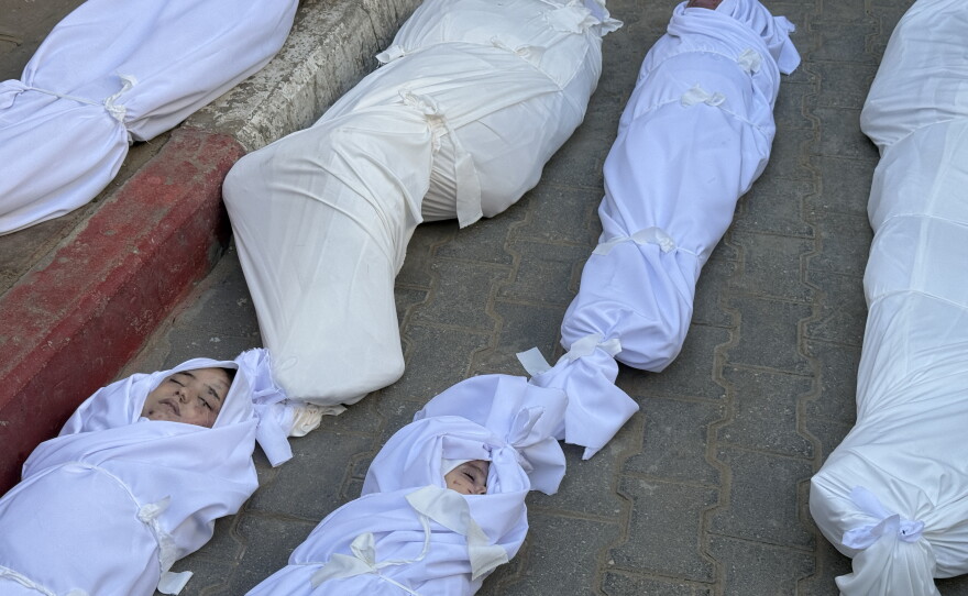The bodies of multiple people, including children, are covered in shrouds at a morgue at Al-Shifa Hospital on Nov. 20, 2025, after Israeli airstrikes targeted homes and tents.