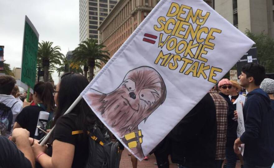 A woman holds a sign that says "Deny Science=Wookie Mistake."