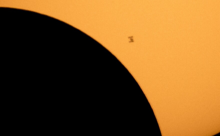 In this image made available by NASA, the International Space Station is silhouetted against the sun during a solar eclipse Monday, Aug. 21, 2017, as seen from Ross Lake, Northern Cascades National Park in Washington state.