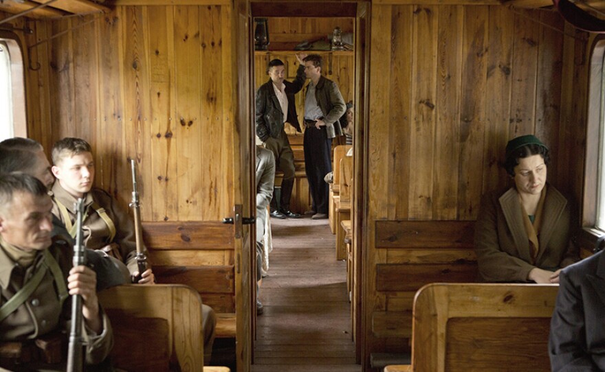 Mercier (DAVID TENNANT) and Colonel Pakulski (MARCIN DOROCINSKI) on the train that is smuggling gold out of Poland, with soldiers in the foreground.