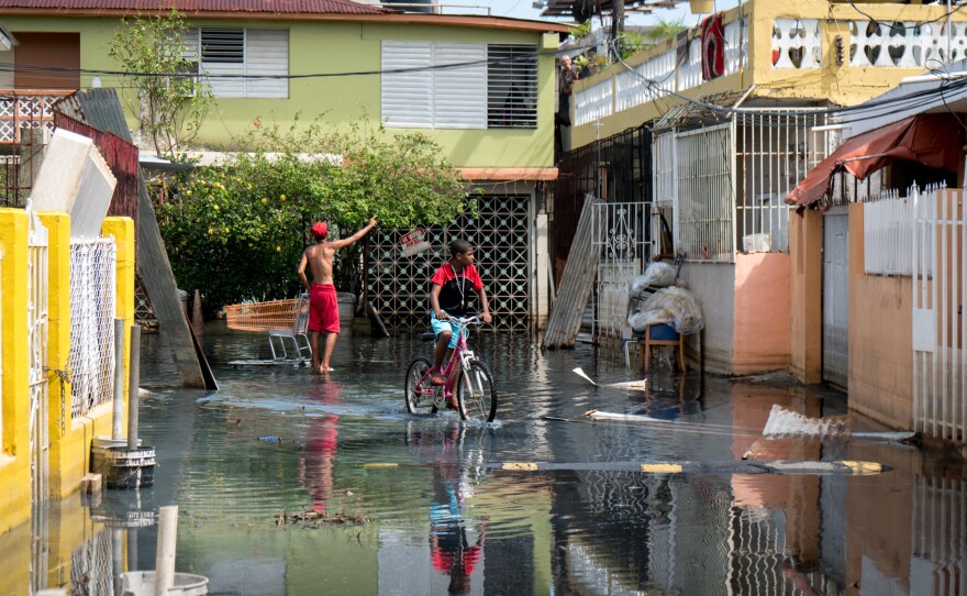 Children walk through standing flood water in the Playita neighborhood. There are small signs that the situation here is improving – but for the residents living through it, the progress is painfully slow.