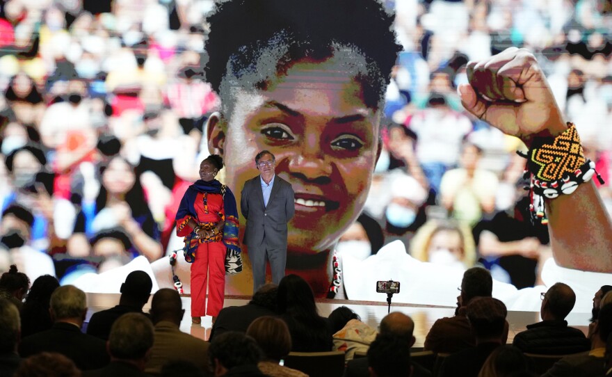 A large image of Francia Márquez is projected on a screen as she and presidential candidate Gustavo Petro stand on stage during a campaign event, March 23. Petro's running mate Márquez would be the first Afro-Colombian vice president if they win.