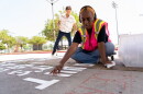 Poet Samira Hassan lays down letters to be burned onto the pavement of a City Heights alley on Tuesday, June 18, 2024.
