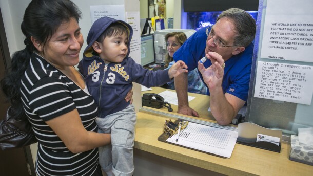 Pediatrician Charles Goodman, talks with patient Carmen Lopez, 37, holding her 18-month-old son, Daniel after being vaccinated with the measles-mumps-rubella vaccine, or MMR at his practice in Northridge, Calif., Thursday, Jan. 29, 2015.