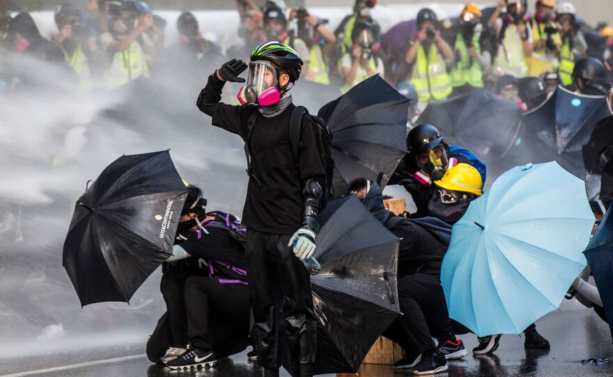 Pro-democracy protesters react as police fire water cannons outside the government headquarters in Hong Kong on September 15, 2019.