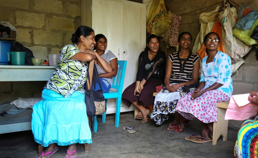 Tamil and Sinhalese workers relax in a former line home that's been converted to a break room while waiting to receive their revenue bonus. After their break they will return to plucking tea.