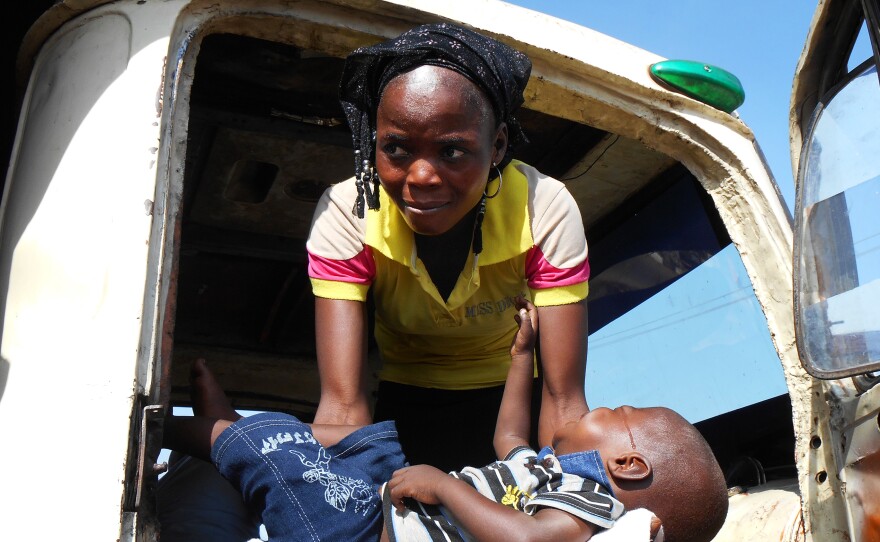 A woman who had fled to Yola to escape fighting in Mubi, at the border with Cameroon, lifts her son into the truck bound for Jos.