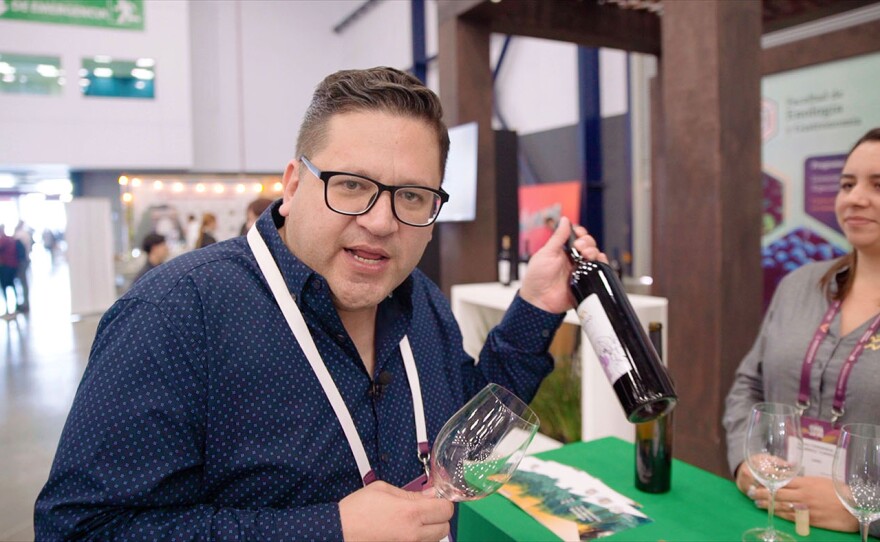 Host Jorge Meraz talks with the staff in the UABC university booth at an international wine event at the Baja Center.