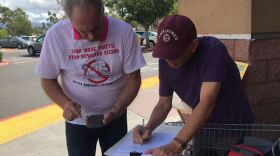 A man signs a petition asking for a referendum to overturn the approval of the Newland Sierra housing development in North County, Oct. 4, 2018.