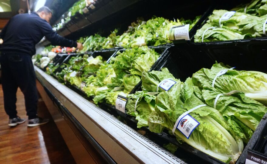 A man shops for vegetables near romaine lettuce for sale at a supermarket in California, where the first death from the E. coli outbreak was reported.