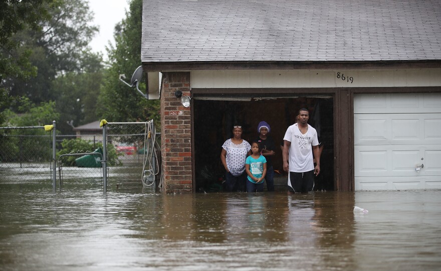 People wait to be rescued from their home after the area was inundated from Hurricane Harvey in Houston on Monday. President Trump travels to Texas on Tuesday.
