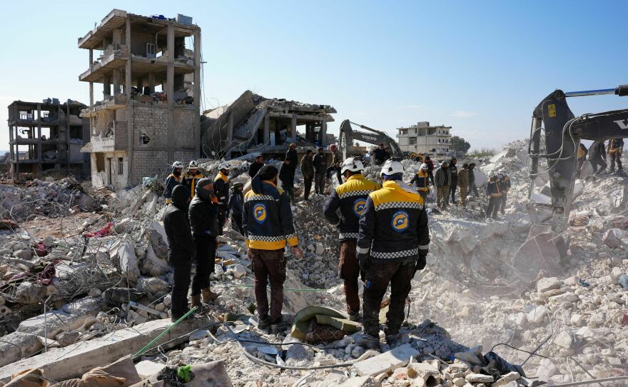 Rescue workers look for survivors amid the rubble of a building in the rebel-held town of Jindayris, Syria.
