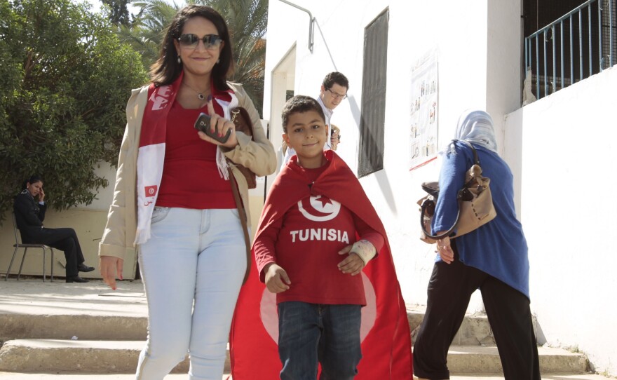 A voter raises her ink-stained finger after voting in Tunis Sunday. Tunisians voted in parliamentary elections that bring full democracy finally within their reach, in the cradle of the Arab Spring.