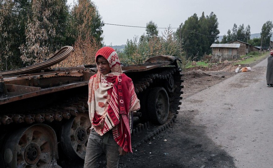 Residents walk past an abandoned tank on a main road in Amhara region, Ethiopia, in 2021, where hundreds of thousands of people have fled recent fighting — and in need of humanitarian assistance.