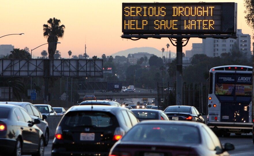 Morning traffic makes its way toward downtown Los Angeles along the Hollywood Freeway past an electronic sign warning of severe drought.