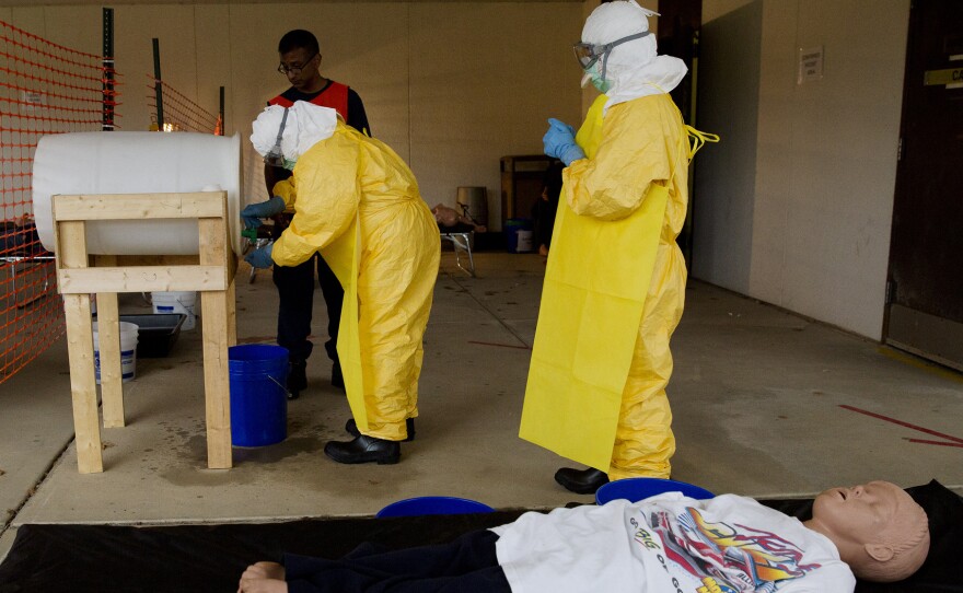 At a CDC training session for clinicians headed to West Africa, a medical workers  practices sanitizing hands after drawing blood from a manikin that's playing the role of an Ebola patient.