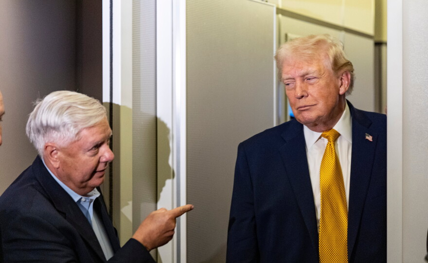 FILE - Sen. Lindsey Graham, R-S.C., left, gestures as President Donald Trump speaks with reporters while in flight on Air Force One, Jan. 4, 2026, as they were returning to Joint Base Andrews, Md.