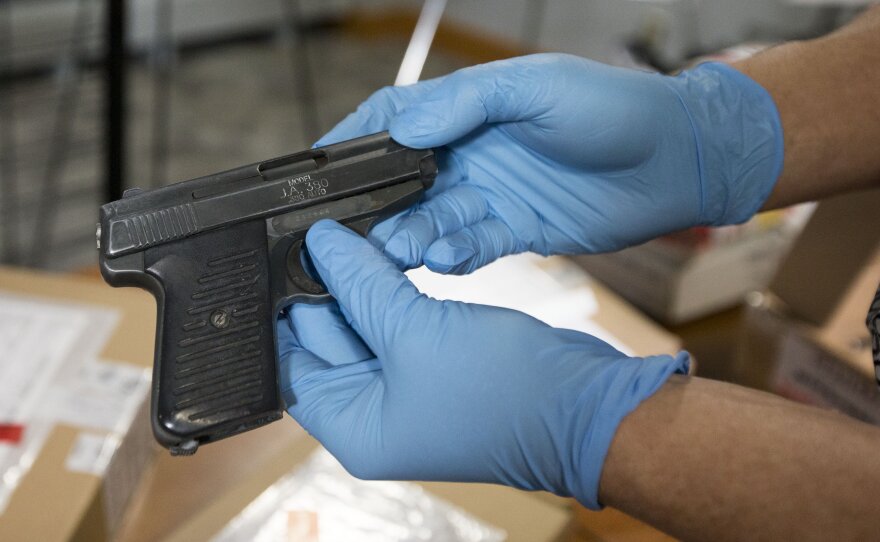 A detective with the gun and gangs task force removes weapons after a news conference on Project Sizzle, an effort by Toronto Police to crack down on gangs in the city.