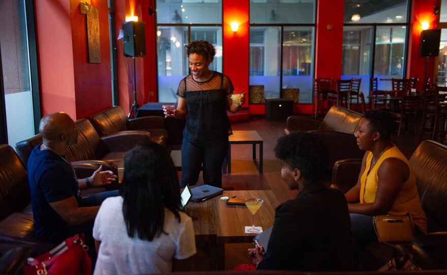 Nicole Muse-Dennis (center) has two jobs. By day she's a school teacher, and by night a manager at a bar in Charlotte.