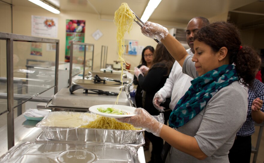 Amaya Weiss, who runs the food pantry at the John Still K-8 School in Sacramento, serves up a spaghetti dinner at the school's monthly family night.