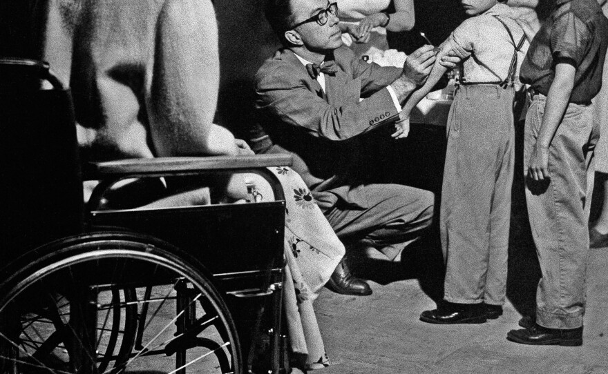 Mrs. Harry C. Spitzer, left, the 1955 national "Polio Mother of the Year," watches Dr. Francis Sullivan as he gives her two children a Salk vaccine inoculation in Glen View, Illinois, May 6, 1955. The boys are, Stephen, left, 6 ½, and Robert, 8. Mrs. Spitzer was stricken with paralytic and respiratory polio in August 1951.