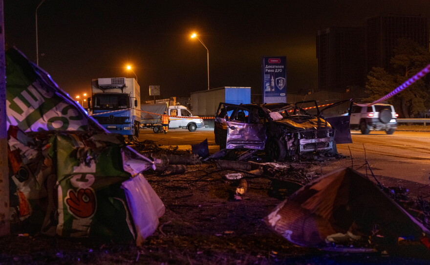 Emergency workers clear debris and damaged road infrastructure near a destroyed car following a Russian overnight strike in Kyiv, Ukraine, Tuesday, Oct. 27, 2026.