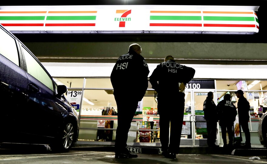 ICE agents serve an employment audit notice at a 7-Eleven in Los Angeles Wednesday. Agents raided 98 stores across the country.