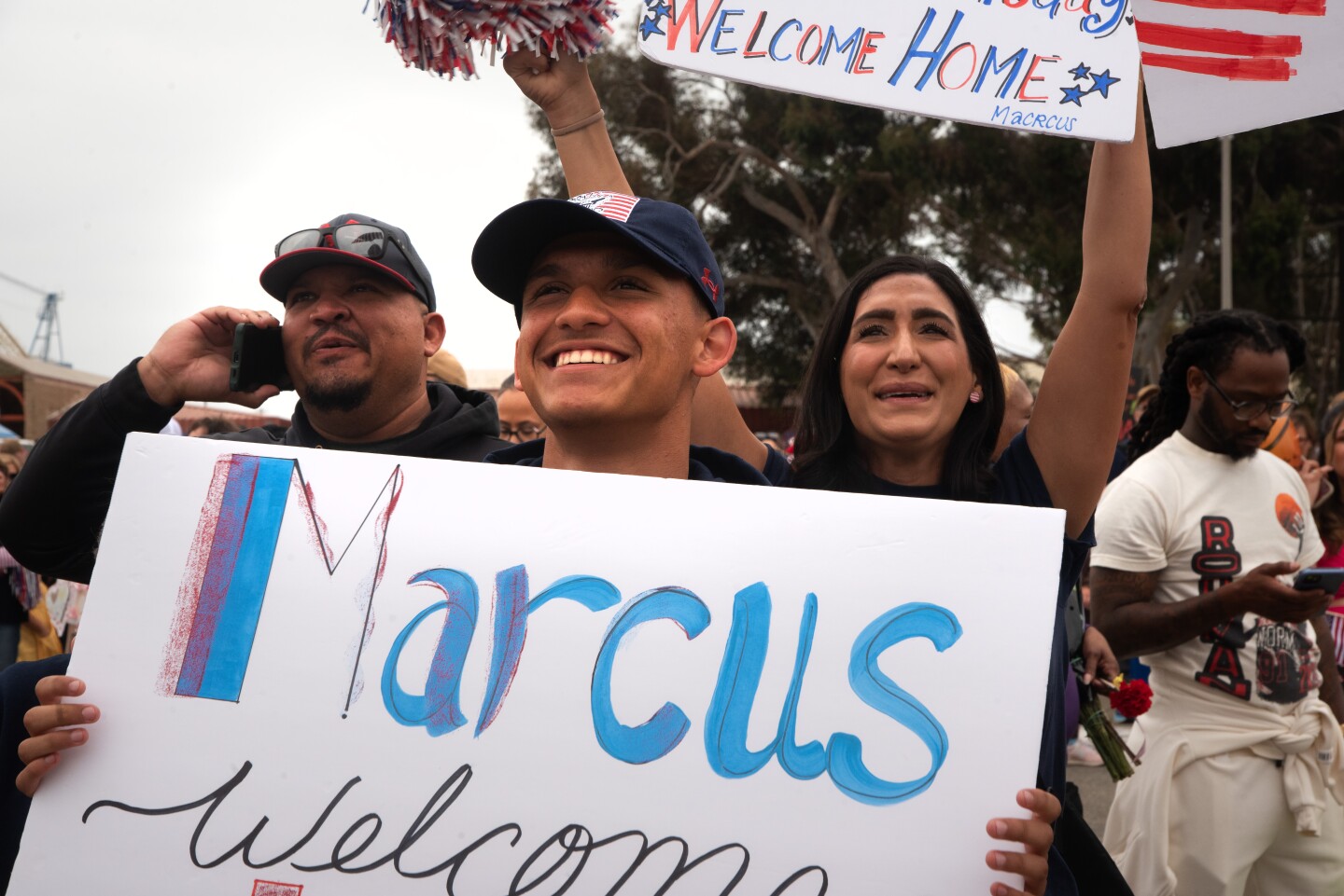 A family waits outside the Naval Air Station North Island dock holding a sign that says "Marcus welcome home" on Oct. 15, 2024.